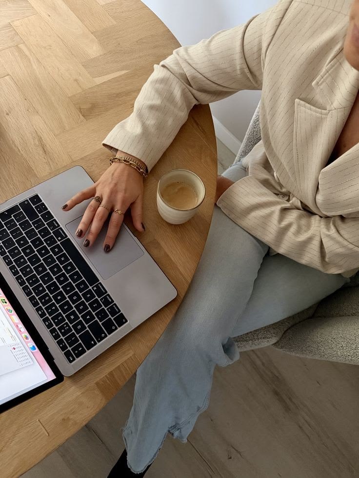 A coach working at her laptop with a coffee